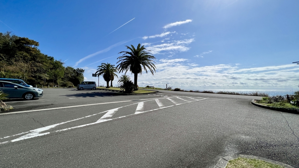 車が並ぶ広々とした駐車場と周囲の緑が広がる様子