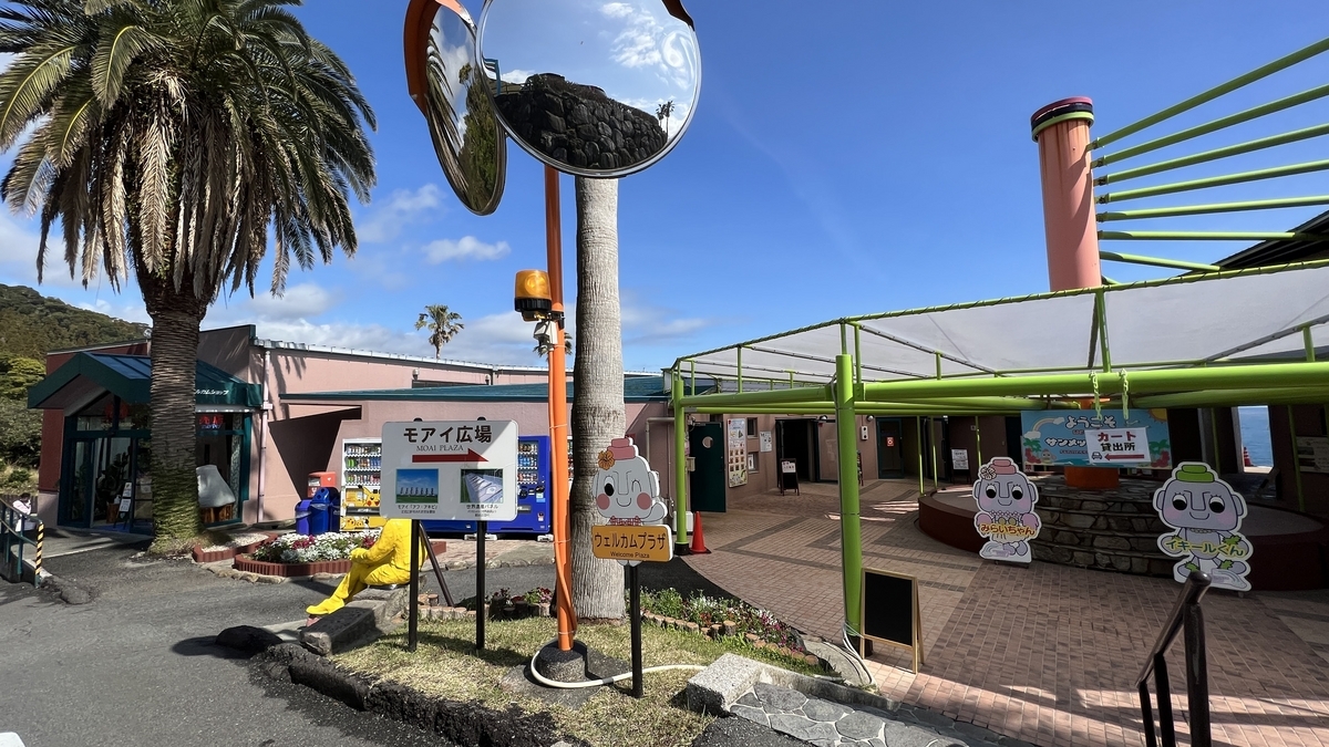 ヤシの木と案内看板が立つウェルカムプラザ周辺の入口風景