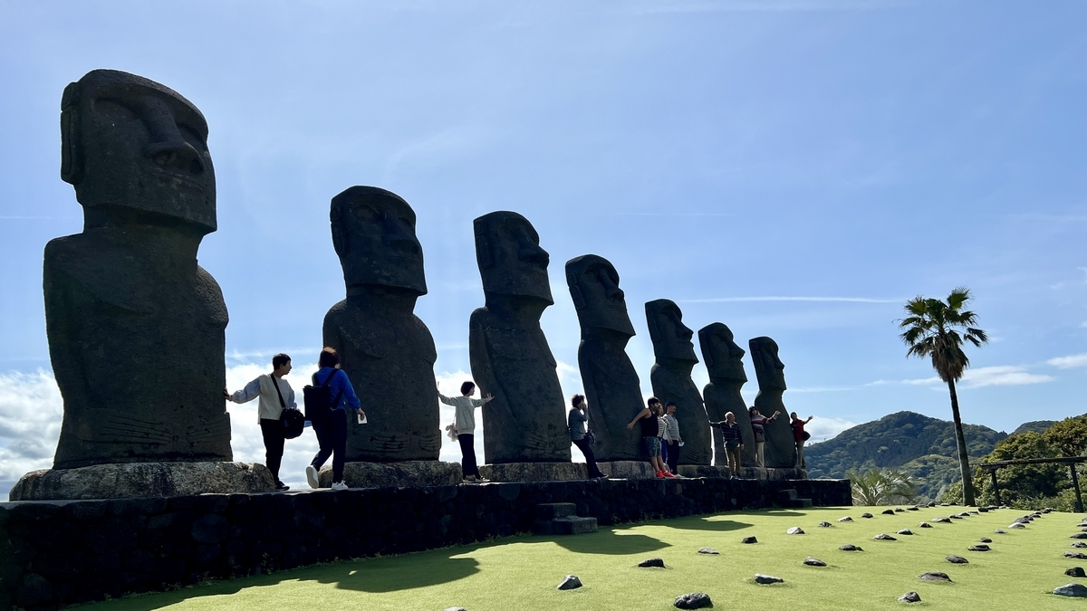 青空の下でモアイ像の前ではしゃぐ来園者たち