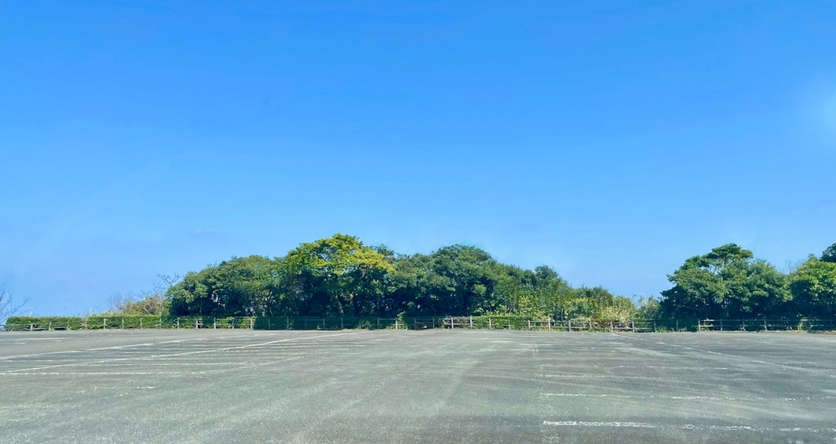 ภาพมุมกว้างของลานจอดรถที่ 2 ที่ล้อมรอบด้วยต้นไม้สีเขียว