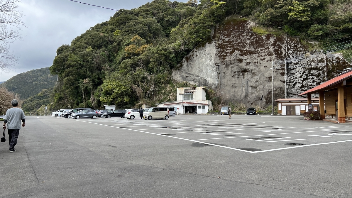 บริเวณป้ายรถเมล์ในลานจอดรถนักท่องเที่ยวและผนังหินด้านหลัง