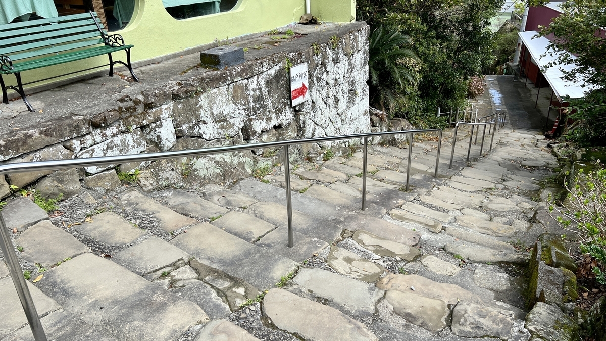 ทางเดินปูหินของเนินฮัตจโชซะกะพร้อมราวจับและต้นไม้ริมทางลาด