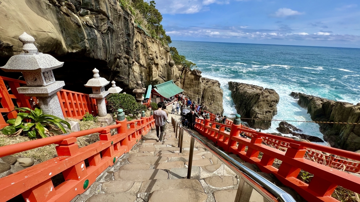 以蓝色大海为背景沿石阶走向本殿洞窟的参拜者