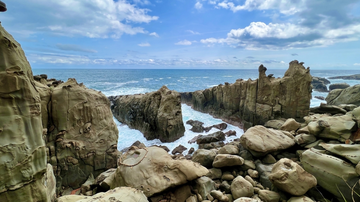 被波浪冲刷的岩石连绵的海岸线和参道的朱红色栏杆