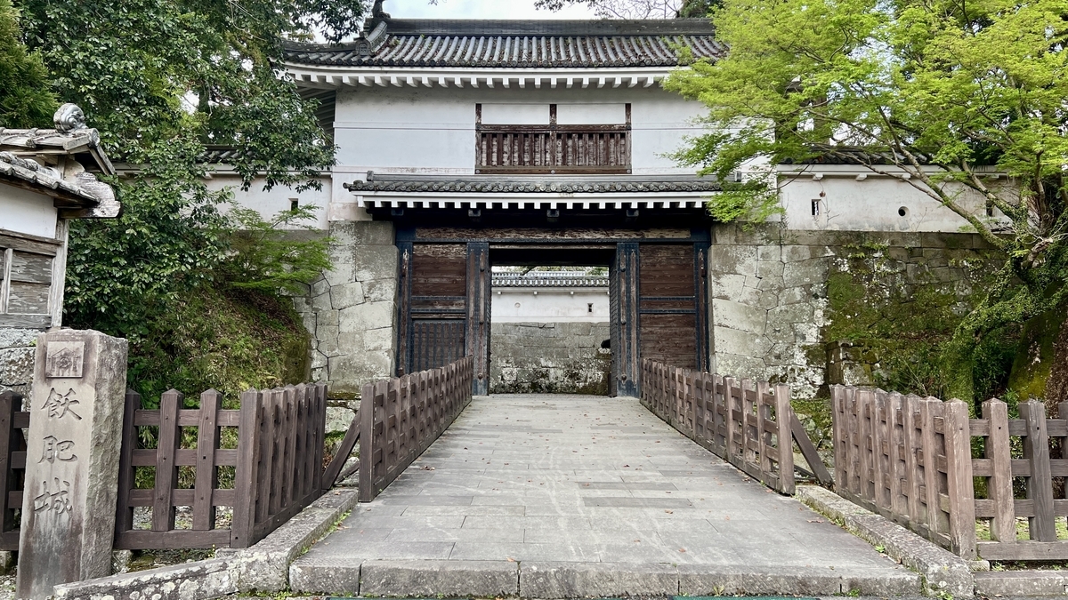 มุมมองด้านหน้าประตูโอเตะมงปราสาทโอบิพร้อมกำแพงหินและประตูไม้ที่ดูน่าเกรงขาม