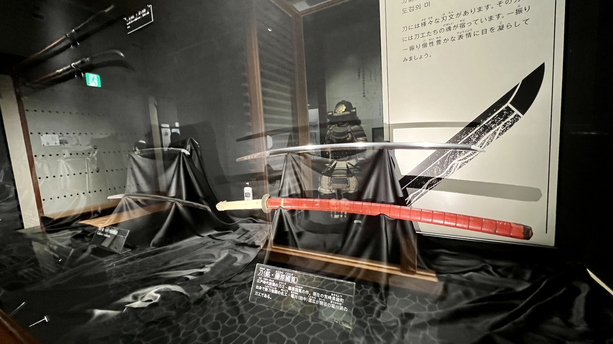 ดาบญี่ปุ่นในตู้จัดแสดงพร้อมแผงข้อมูลด้านหลัง