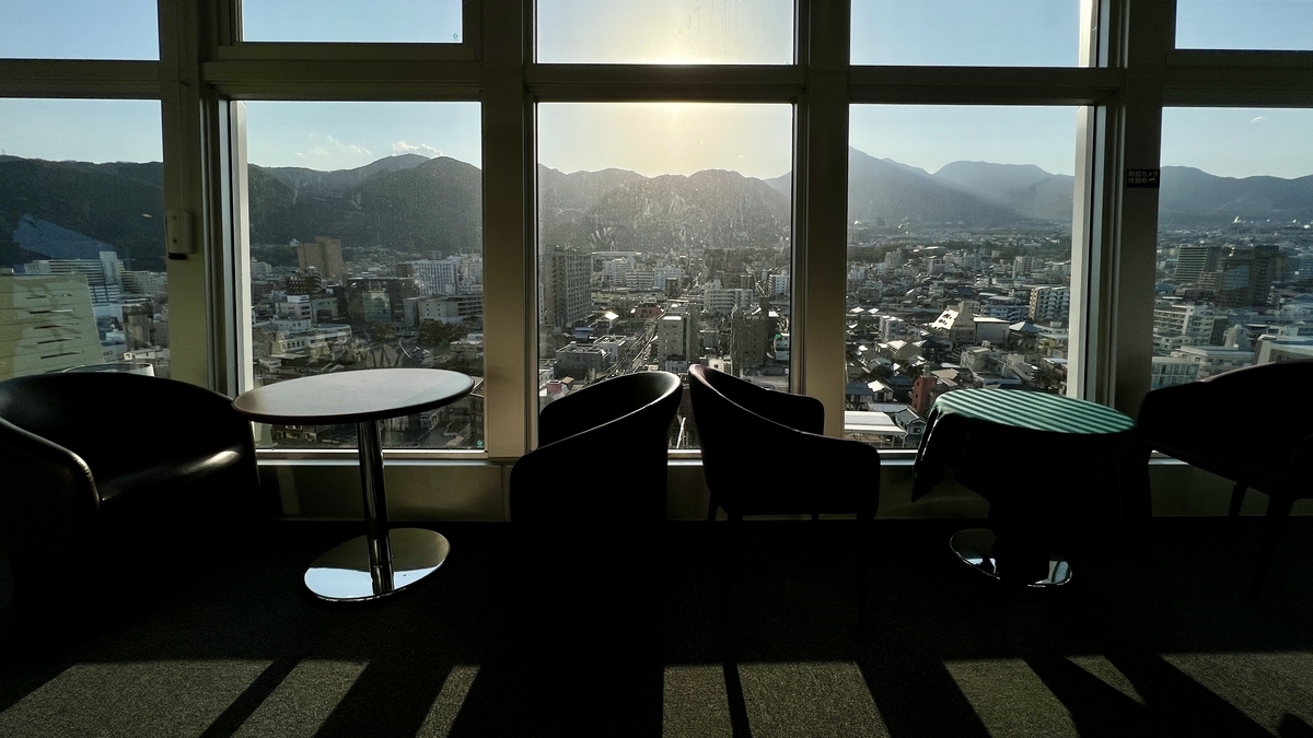 傍晚逆光中展望台椅子的剪影和窗外别府市区