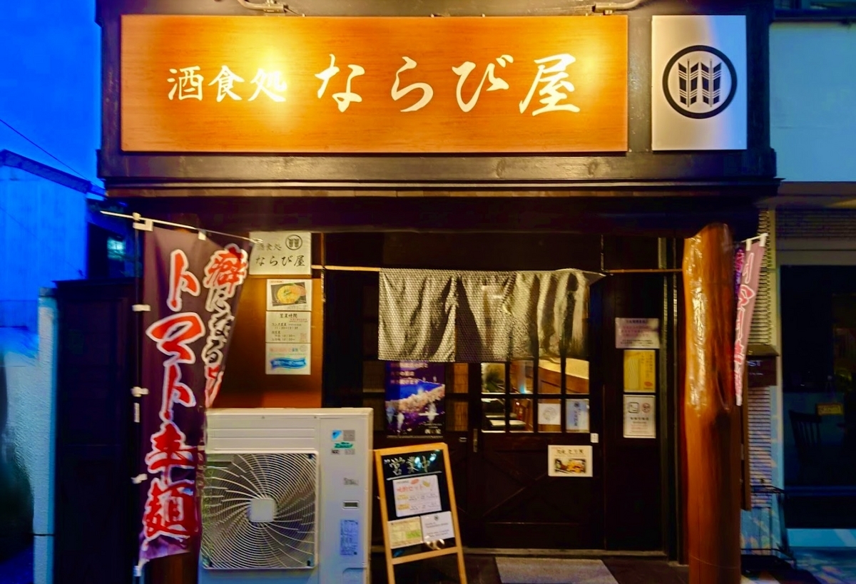 Letrero de madera y cortina noren en la entrada de Narabiya al atardecer