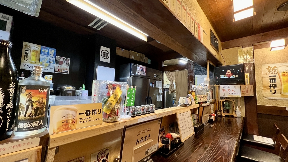 Vista interior mostrando la barra con menús y botellas, con TV al fondo