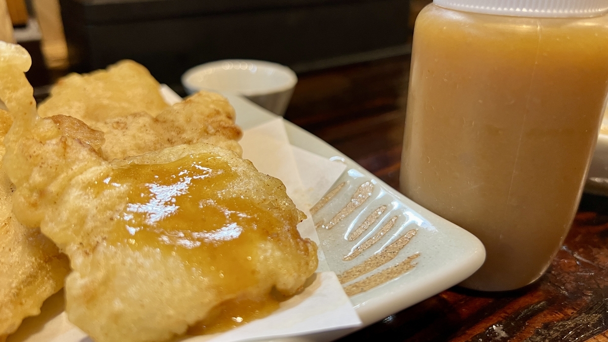 Toriten con salsa rociada encima, botella de aderezo junto al plato