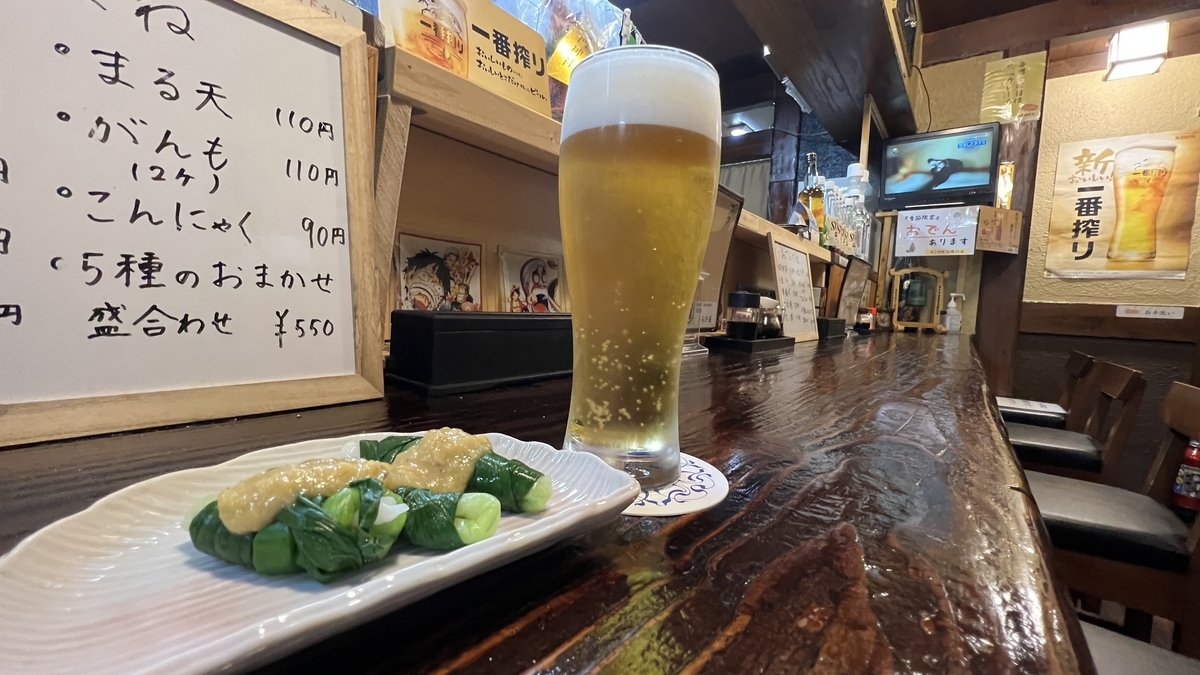 Vista del asiento de barra con pequeño plato y cerveza de barril, interior extendiéndose al fondo