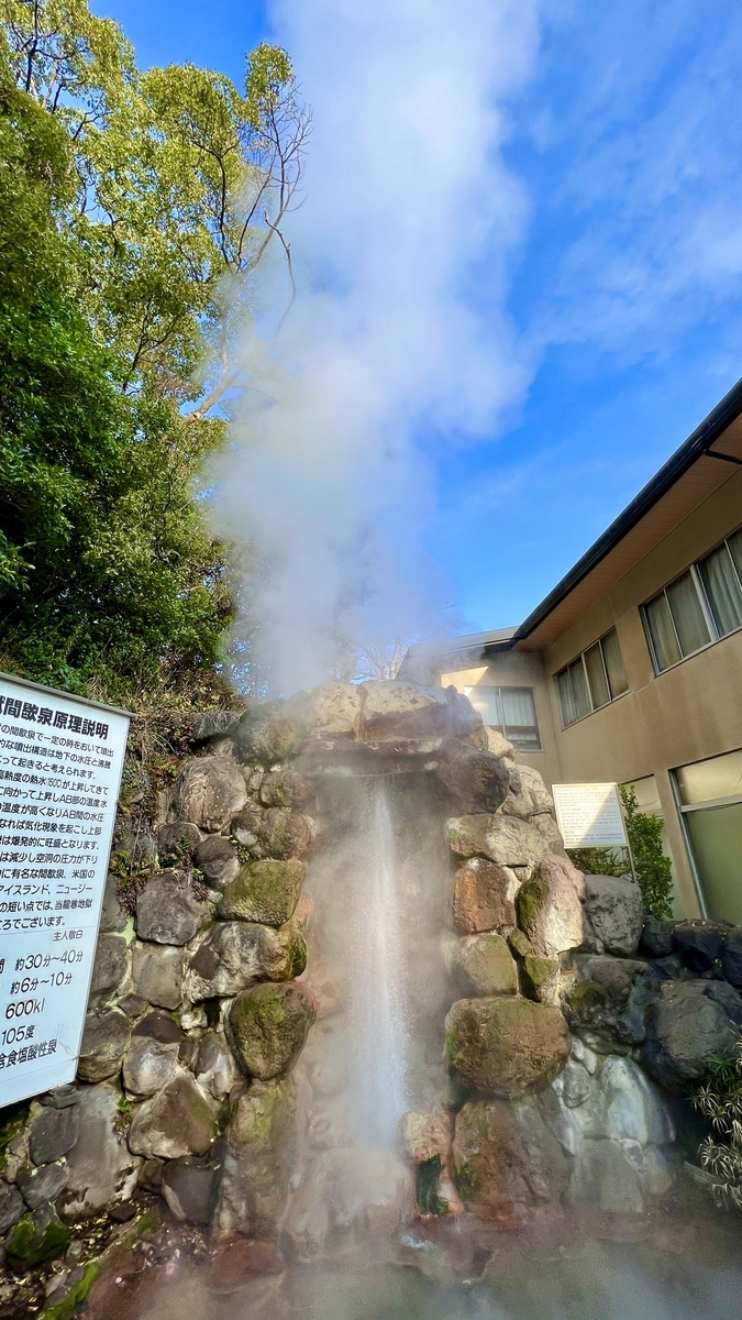 藍天為背景,岩石噴口處白色蒸氣猛烈上升