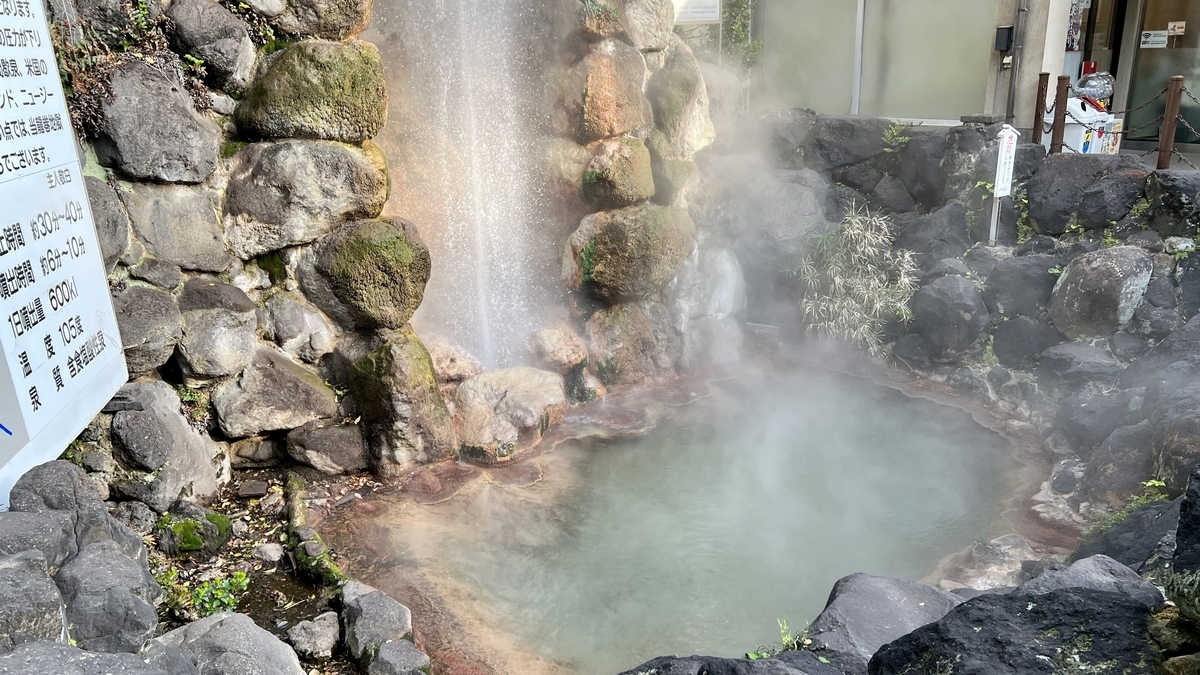 噴口旁蒸氣升騰的綠色溫泉池與石圍欄