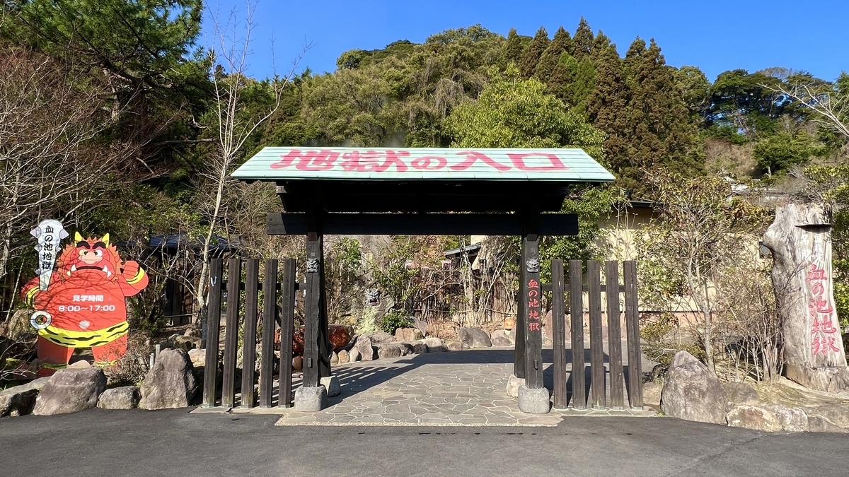 Puerta negra y cartel rojo de oni en la entrada de Chinoike Jigoku