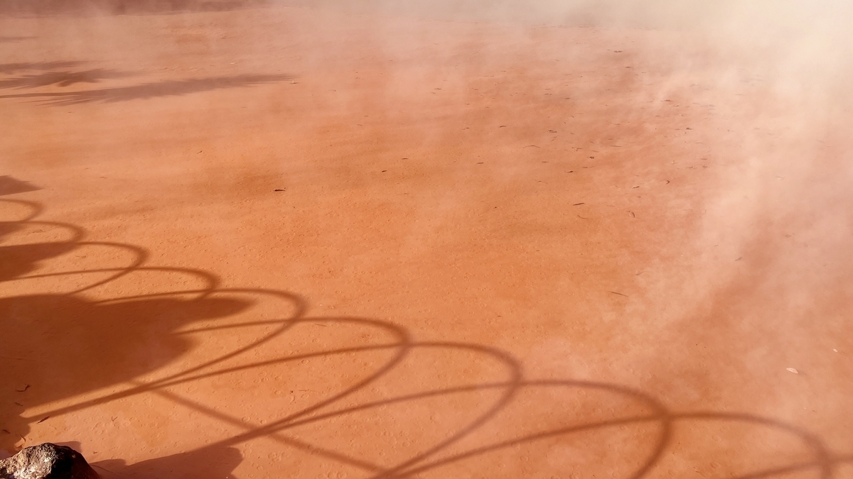 Piscina de barro caliente marrón rojizo con sombras de barandillas curvas en la superficie del agua