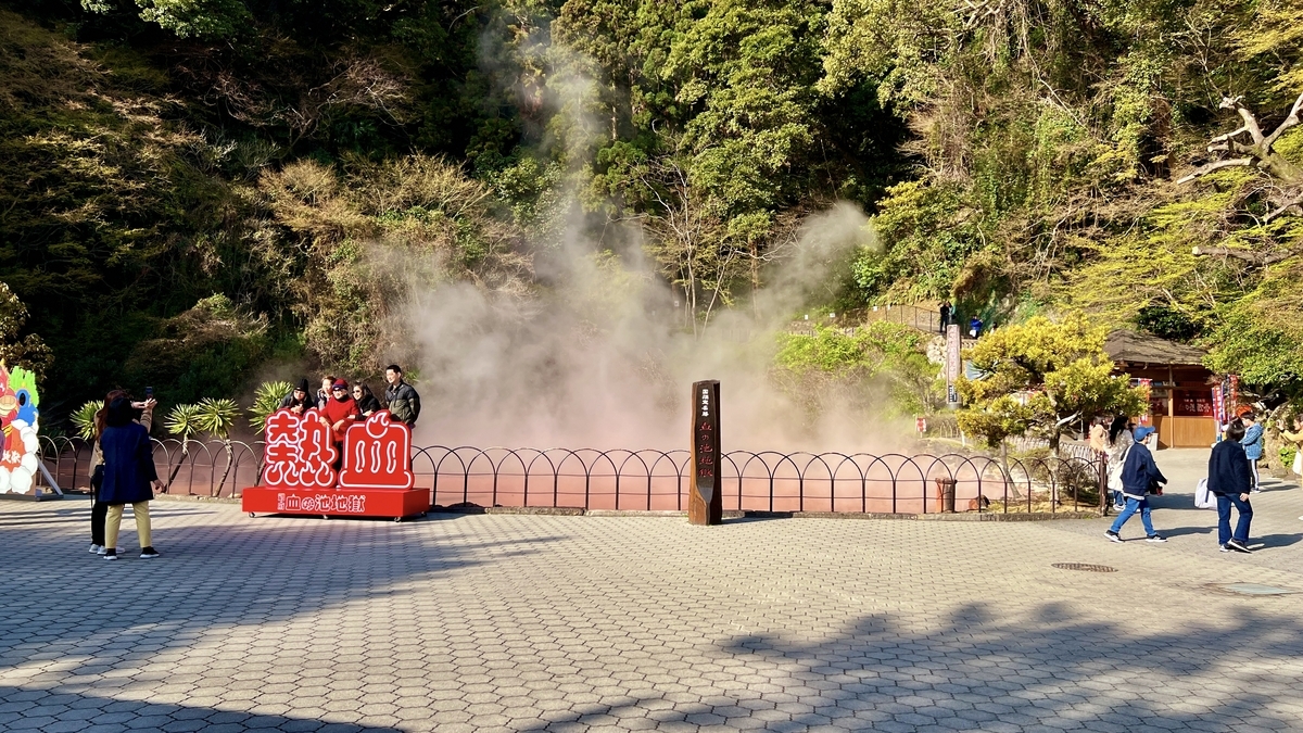 Turistas tomando fotos frente a la piscina humeante con cartel de Nekketsu