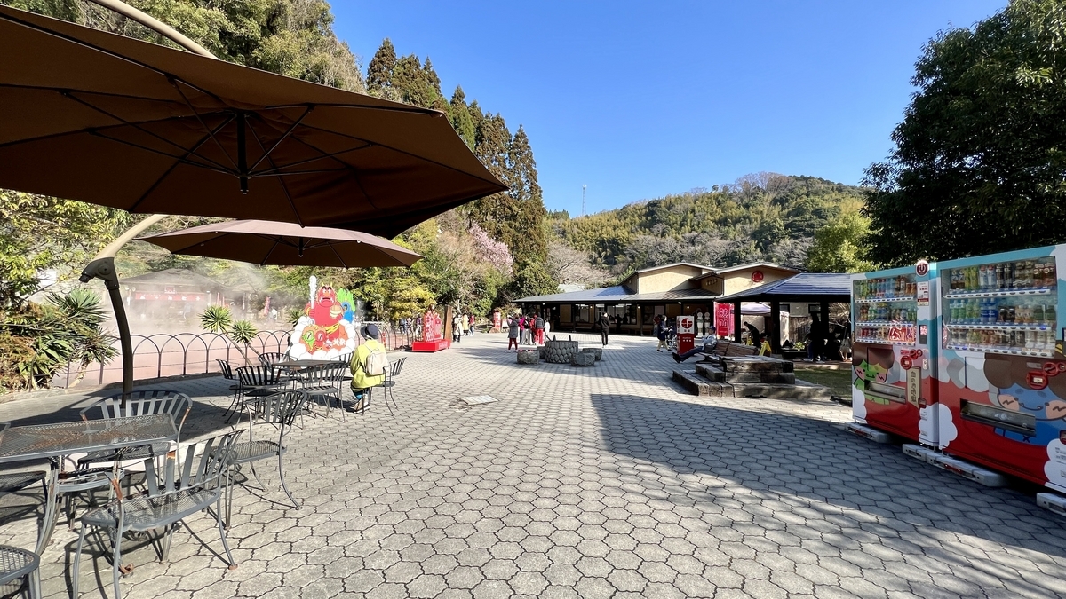 Mesas con sombrilla y máquinas expendedoras en la plaza de descanso de Chinoike Jigoku