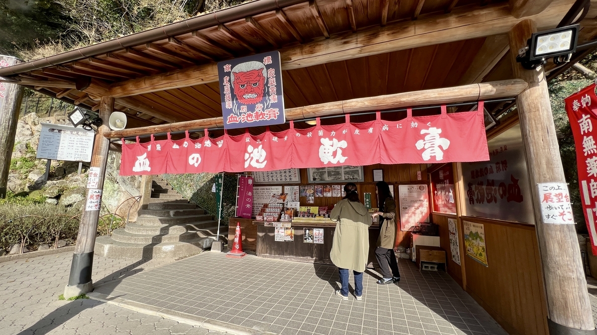 Turistas explorando productos bajo cortinas noren rojas en la tienda de Chinoike Nanko