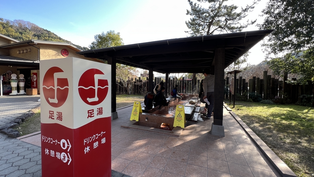 Cartel de información del baño de pies y área de baño de pies cubierta con visitantes remojando sus pies