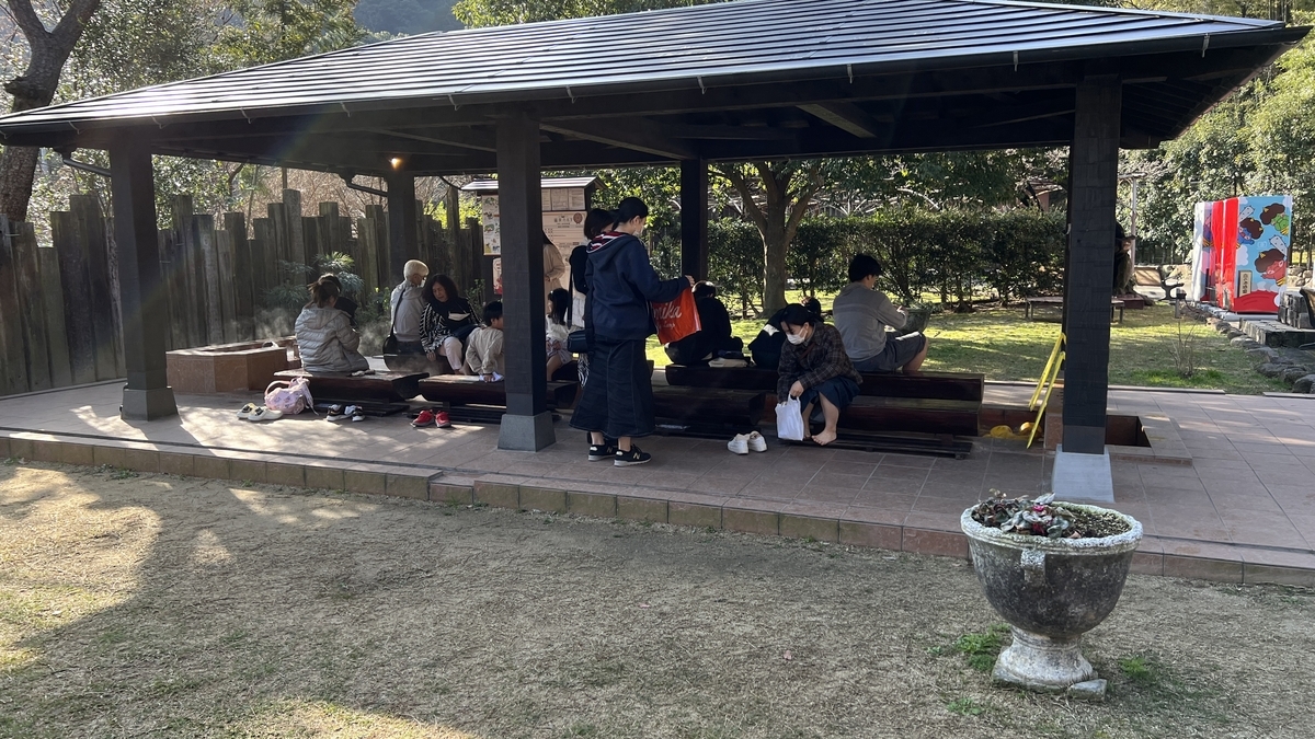 Baño de pies cubierto lleno con muchos visitantes sentados disfrutando del agua caliente