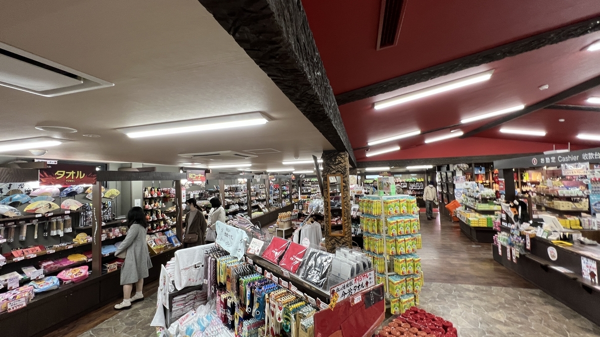 Tienda espaciosa con techo rojo mostrando toallas, dulces y recuerdos en Chinoike Jigoku