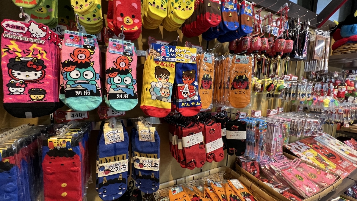 Exhibición en la pared de calcetines y llaveros con temas de oni y Beppu en la esquina de recuerdos
