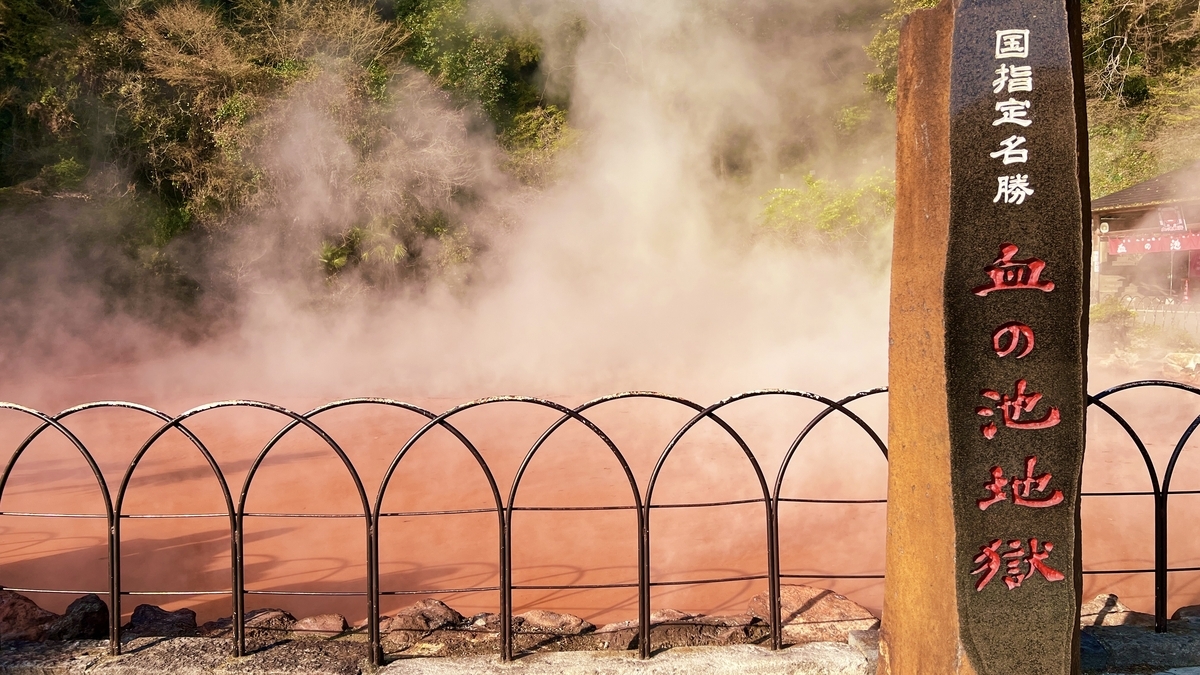 Monumento de piedra de Chinoike Jigoku frente a la piscina roja y el vapor
