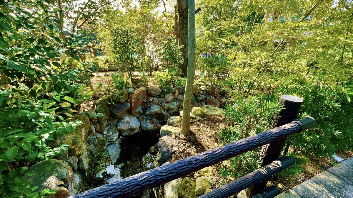 시라이케 지고쿠 일본 정원의 석조물과 작은 수로를 내려다보는 나무 난간