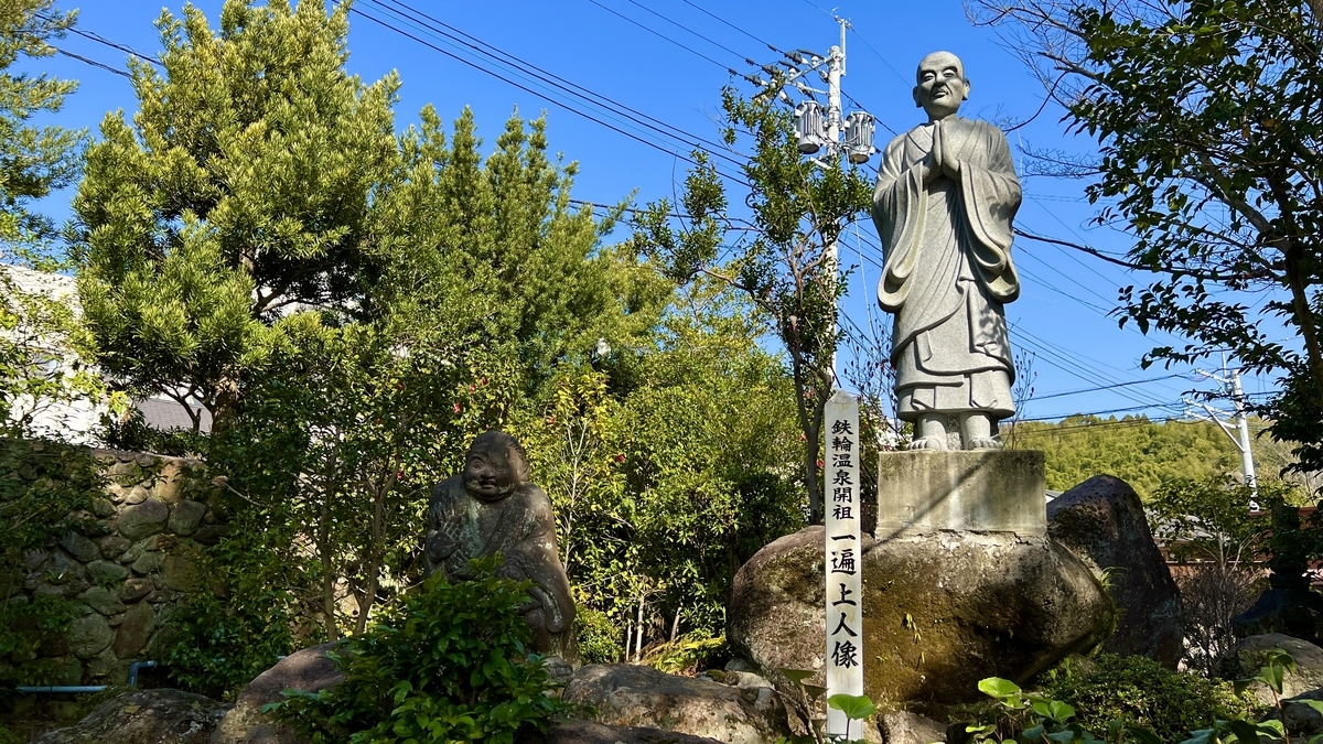 시라이케 지고쿠 정원에 서 있는 잇펜 상인 동상과 받침대 앞 석주