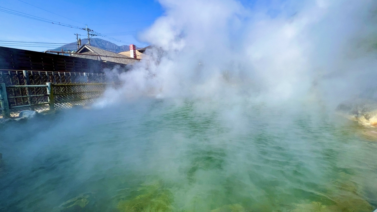 증기가 소용돌이치는 오니야마 지고쿠의 뜨거운 수면과 뒤편 시가지