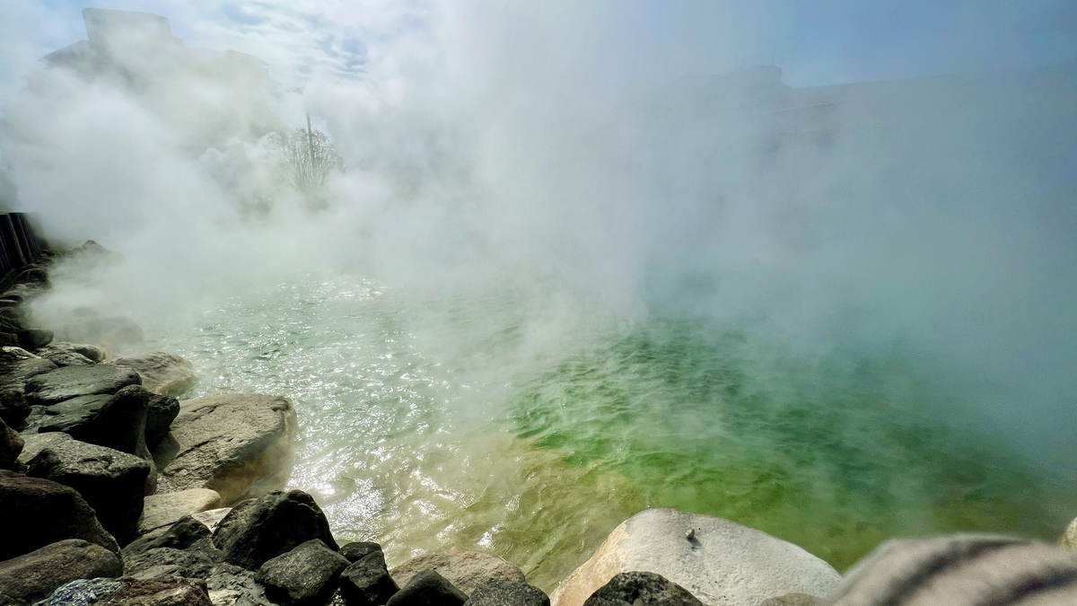 짙은 증기에 휩싸인 오니야마 지고쿠 연못과 녹색 열탕