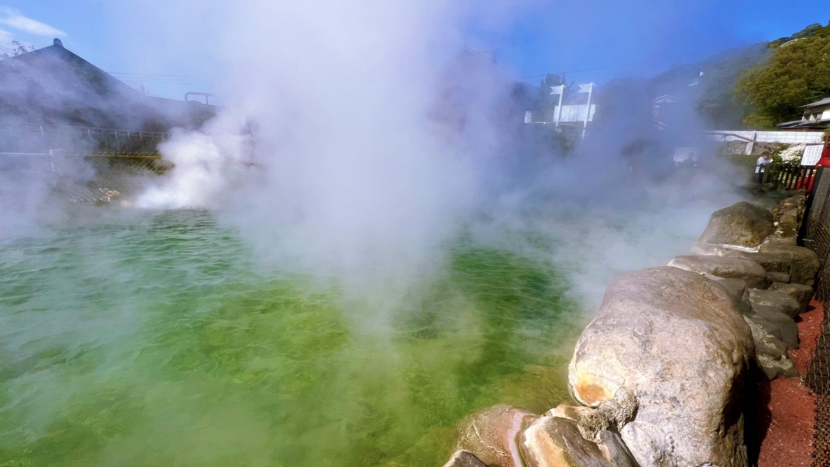 바위에 둘러싸인 오니야마 지고쿠의 녹색 연못과 솟아오르는 흰 증기