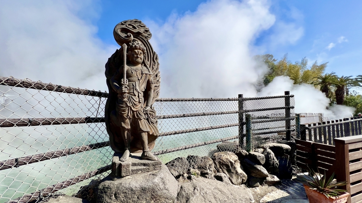 오니야마 지고쿠 연못 앞에 서 있는 부동명왕상과 뒤로 솟아오르는 증기