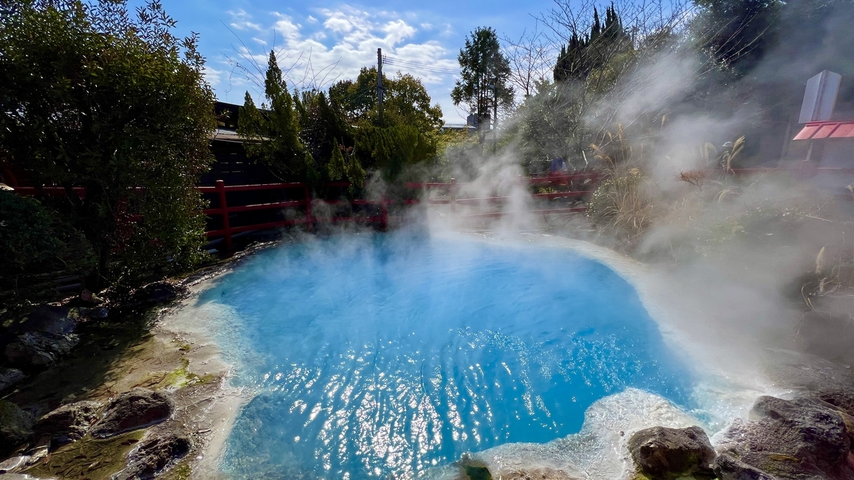 빨간 울타리와 나무들 사이로 증기가 피어오르는 파란 온천