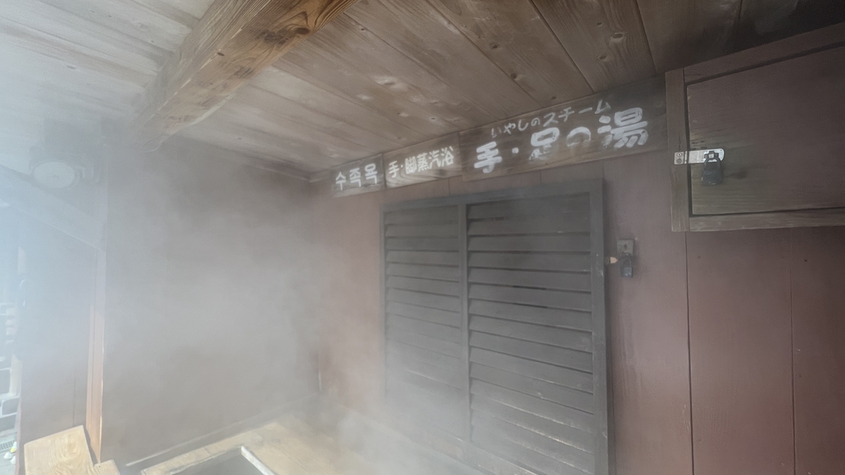 증기에 감싸인 목조 탕집과 입구 안내판