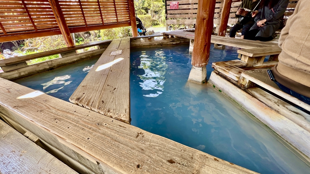 나무 벤치로 둘러싸인 파란 족욕탕에 발을 담근 휴식 공간