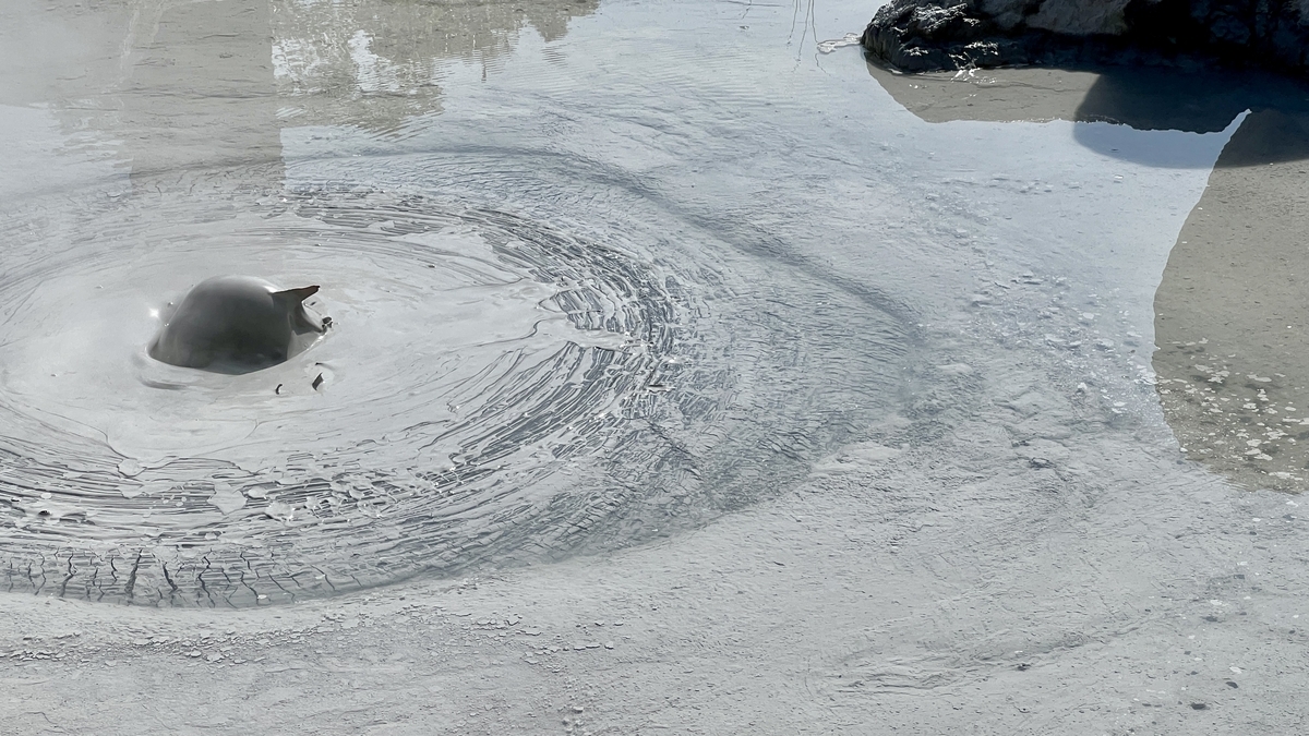 Barro gris caliente elevándose y creando ondas en la superficie de barro de Oniishi Bouzu Jigoku