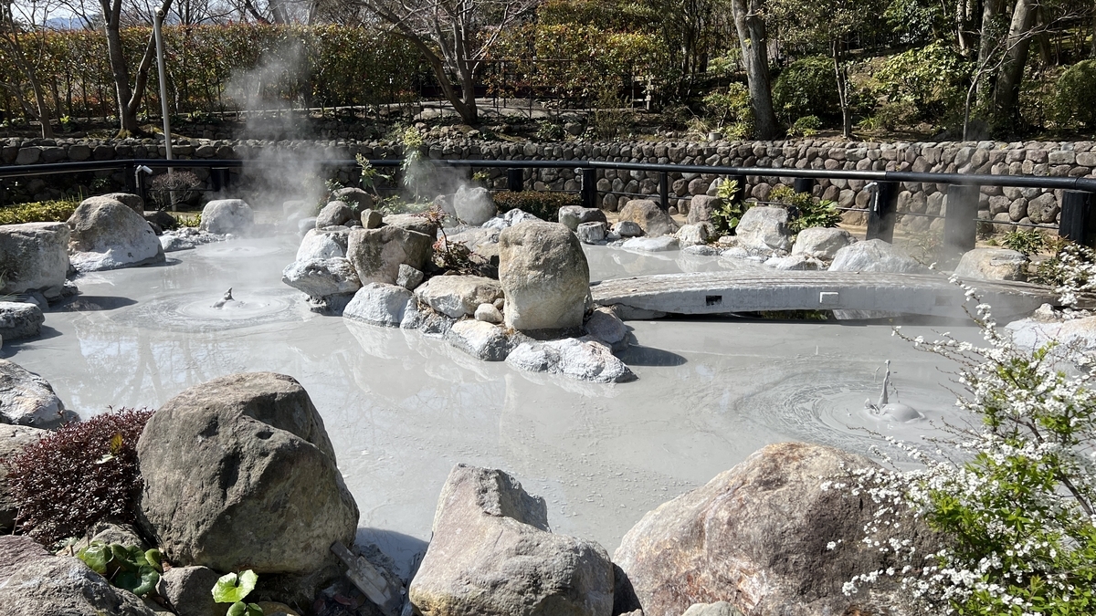 Vista del estanque de barro blanco caliente con vapor ascendiendo en Oniishi Bouzu Jigoku