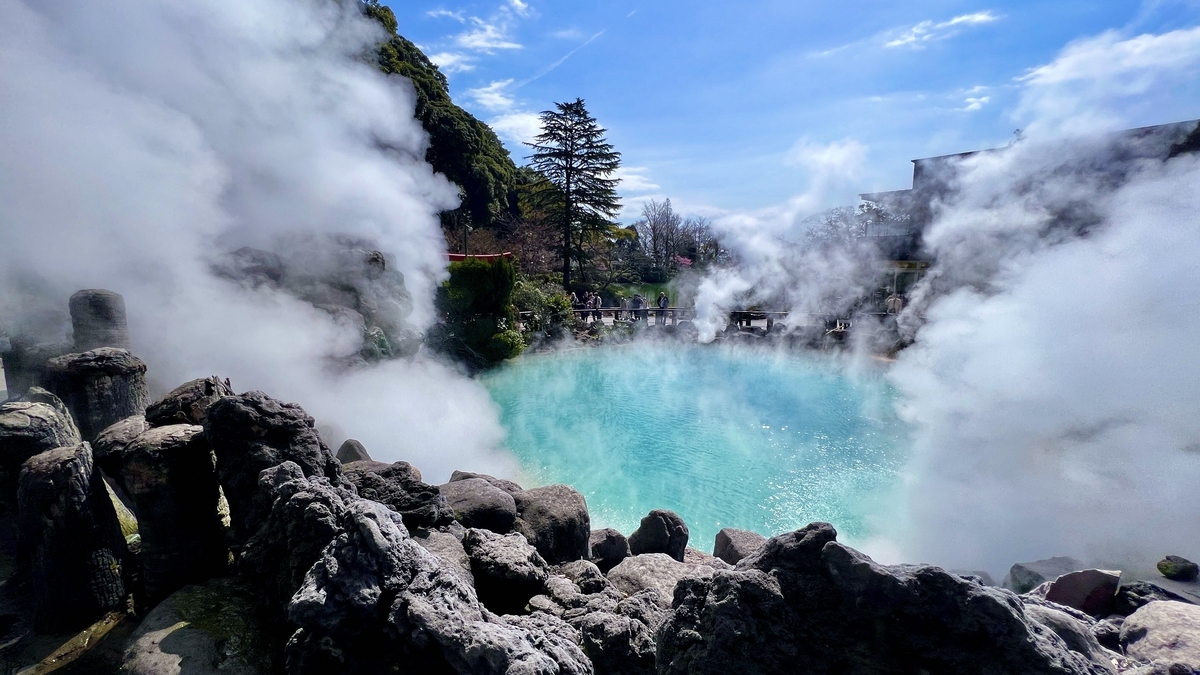 검은 바위와 피어오르는 수증기에 둘러싸인 우미지고쿠의 푸른 온천 웅덩이