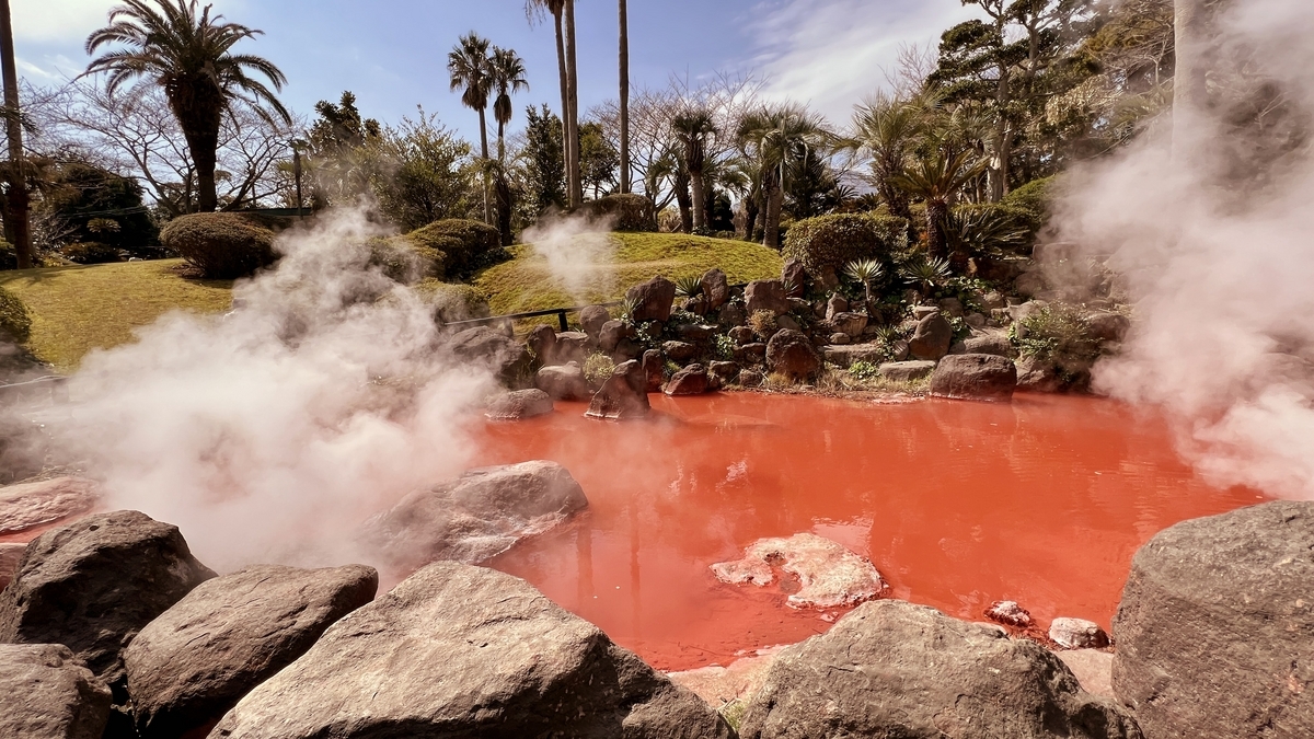 바위 앞에서 본 아카이케지고쿠의 붉은 수면과 피어오르는 수증기