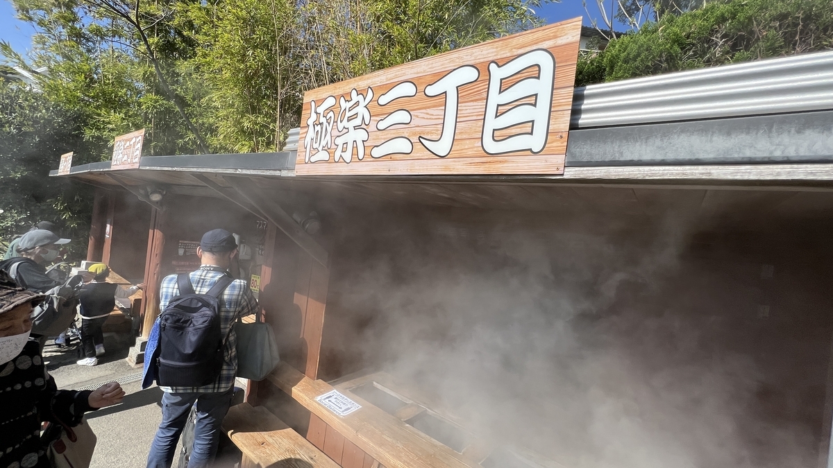 かまど地獄の極楽二丁目で湯気が立ちこめる売店のカウンターと並ぶ来園者