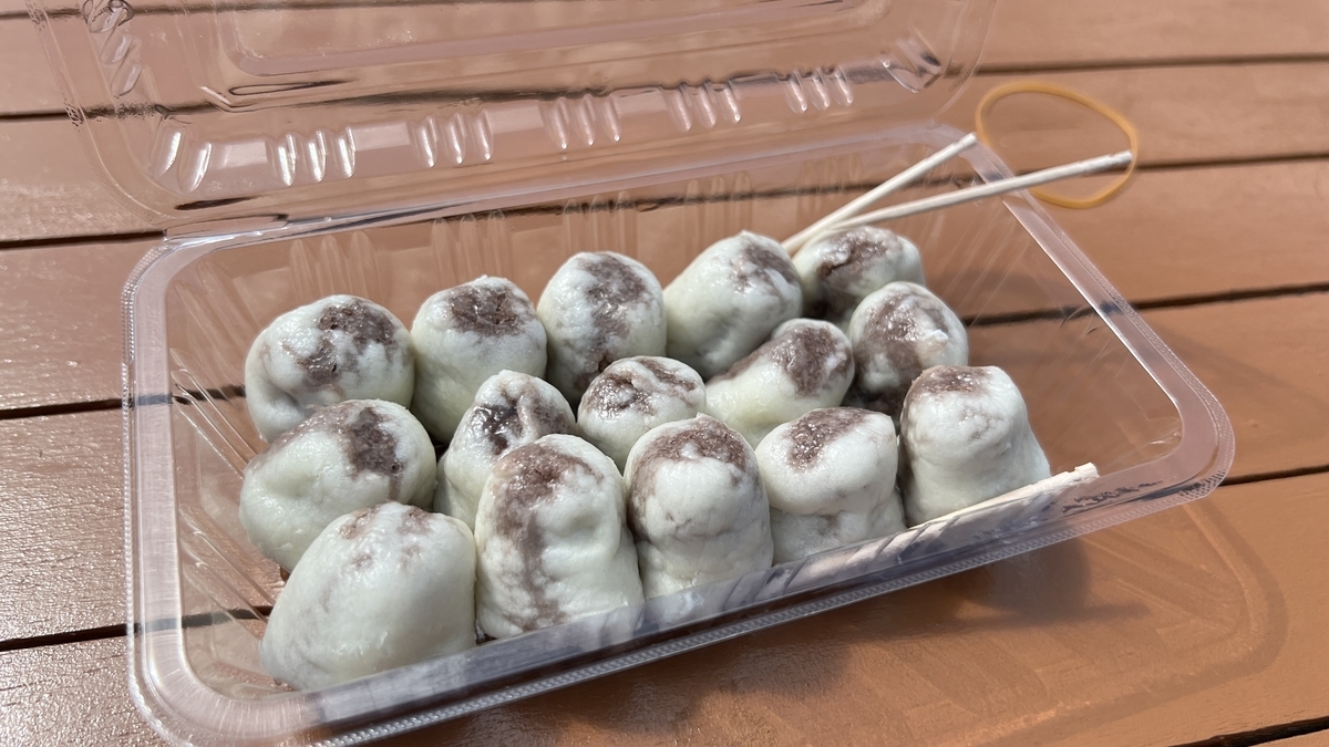 海地獄名物の極楽饅頭がプラスチック容器に並び串が添えられた様子