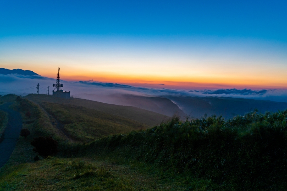晚霞天空与云海上矗立的通信塔和外轮山山脊