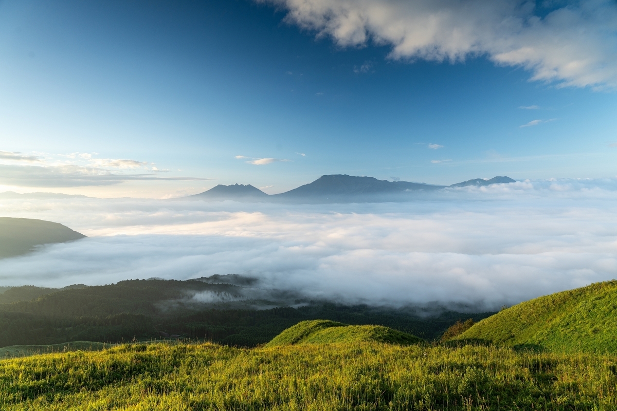 漂浮在云海上的阿苏五岳山脊与前方的绿色山丘