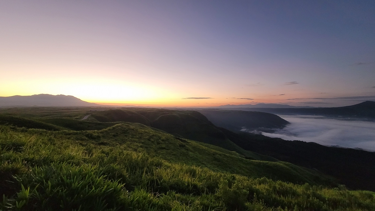 晚霞下绿色山脊连绵、云海流淌的阿苏山脉