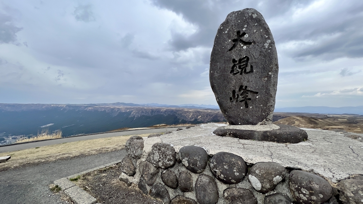 刻有大观峰文字的石碑与背后展开的外轮山