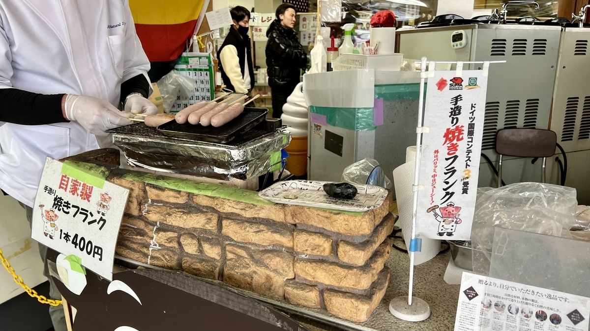 店员在铁板上烤手工香肠与摊位招牌