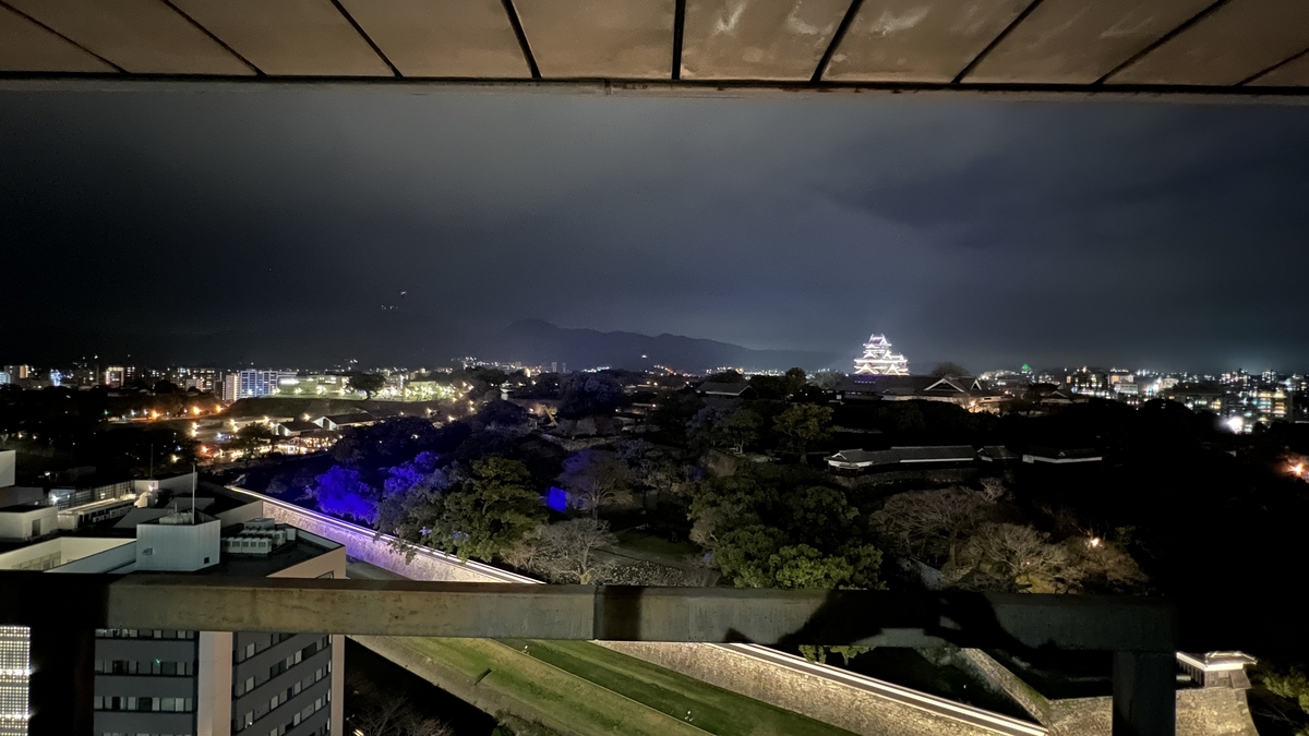 透过观景大厅窗框看到的灯光秀下熊本城天守阁和城内夜景
