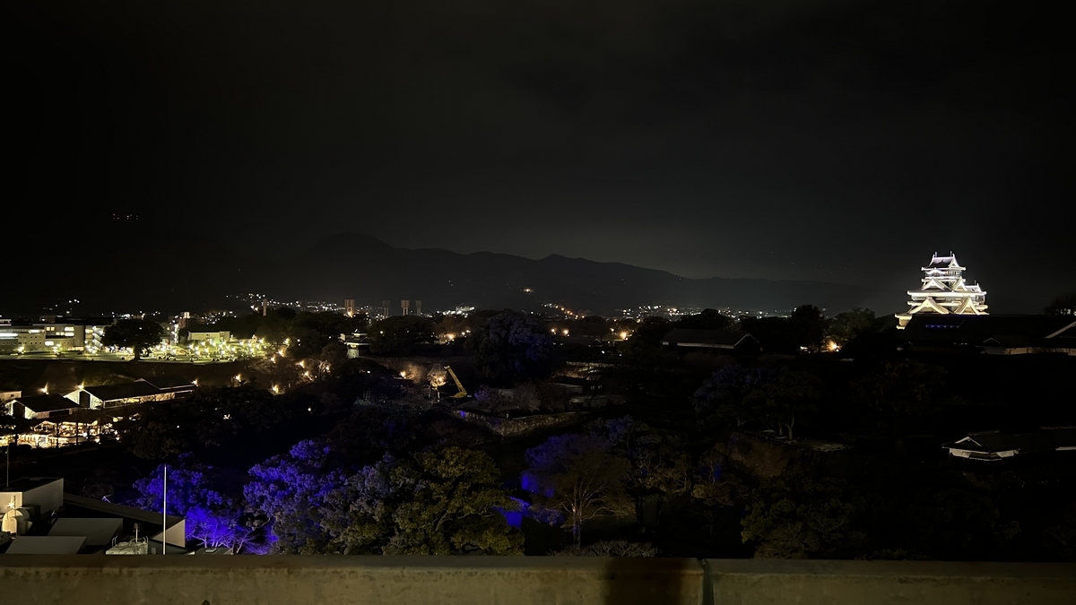 远处发光的熊本城天守阁和灯火通明的市区,夜晚的熊本城公园周边