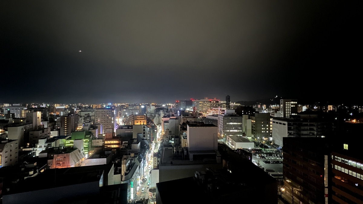从观景大厅俯瞰熊本市中心夜景,街道上排列着霓虹灯和车辆灯光